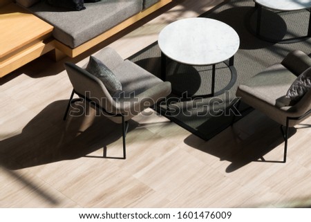 Top view of lobby lounge with long sofa, armchairs ,round tables and grey carpet on marble floor in modern residential building.