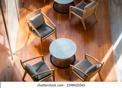 Top View Of Lobby Lounge With Wood Armchairs And Round Tables On Wood Floor In Modern Office Building.