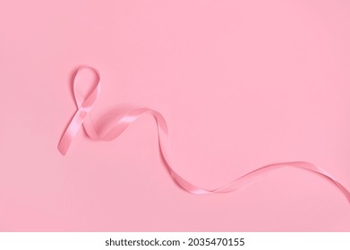 Top view of a long pink satin ribbon, where one end is endless. Breast Cancer Awareness, medical concept isolated on pink background with copy space. October awareness month campaign. - Shutterstock ID 2035470155