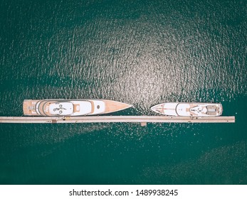 Top view of the luxurious white yachts moored at the long thin quay, blue sea in a sunny day; millionaire concept. - Shutterstock ID 1489938245