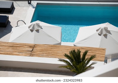 Top view luxury pool with sunshades and white umbrellas, spa hotel summer holidays
