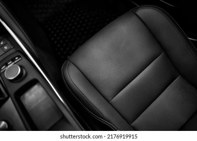 Top view of luxury sport car front passenger leather seat with detail high end fabric and stitch texture along with blurred control button panel. Design element and black car interior background.