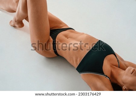 Top view, lying down on the floor. Young caucasian woman with athletic body shape is indoors at daytime.