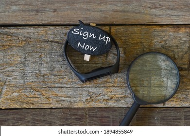 Top view of magnifying glass, watch and wooden tag written with text SIGN UP NOW over wooden background. Business concept.  - Powered by Shutterstock