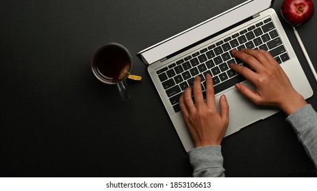 Top View Of Male Hands Typing On Laptop Keyboard On Black Table In Home Office Room 