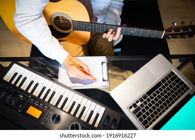 top view of male songwriter writing a song with laptop computer and keyboard on desk. songwriting concept