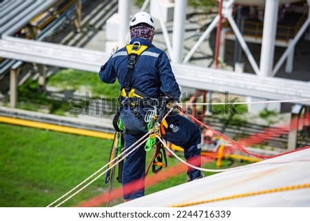 Top view male worker inspection wearing safety first harness rope safety line working at a high place on tank roof spherical gas propane.