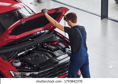 Top view of male worker in uniform that repairs red automobile. - Shutterstock ID 1793842378