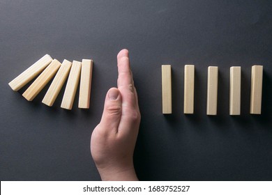 Top View Man Hand Stopping Falling Dominos In A Business Crisis Management Conceptual Image.