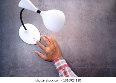 Top View Of Man Hand Turning Lamp On Black Background