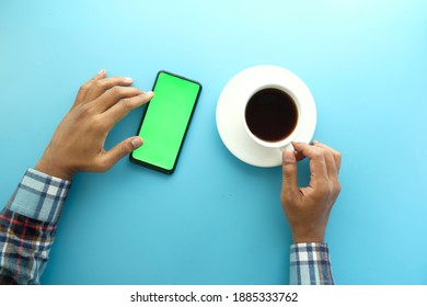 top view of man hand using smart phone and drinking tea 