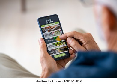 Top view of man hands holding smartphone while order food delivery at home. Back view of mature man using food delivery app with mobile phone to order lunch.  - Shutterstock ID 1681645819