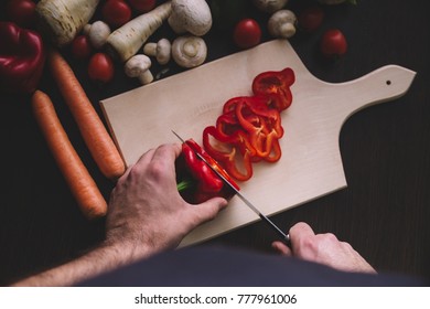 Top view of man hands while cutting red pepper.