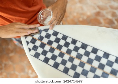 Top view of a man sanding a surfboard using sandpaper - Powered by Shutterstock