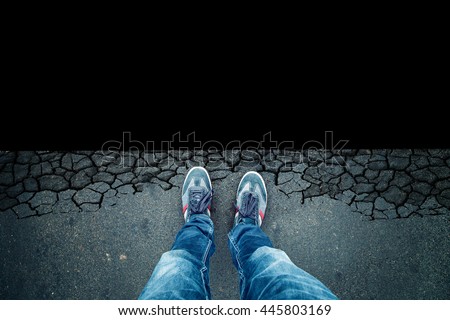 Top view of a man standing in front of the dangerous black abyss background.
