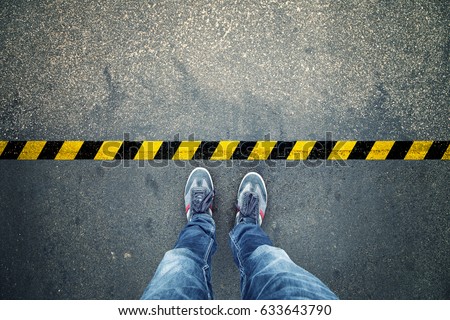 Top view of a man stands on industrial striped asphalt floor with warning yellow black pattern.
