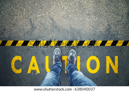 Top view of a man stands on industrial striped asphalt floor with warning yellow black caution pattern.