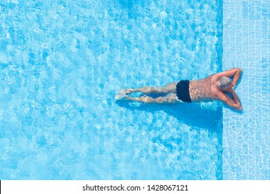 Top View Of A Man Sunbathing In The Pool On A Sunny Day