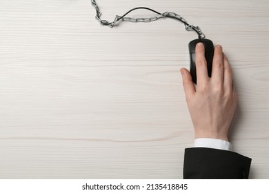 Top view of man using computer mouse at white wooden table, cable with chain. Internet addiction