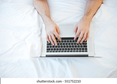 Top View Of Man Using Laptop And Lying On Bed