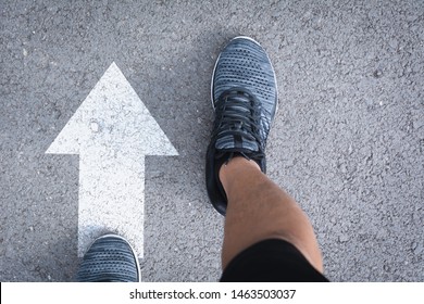 Top View Of Man Wearing Shoes Choosing A Way Marked With White Arrows. Chooses The Right Path Concept.