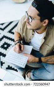 top view of man writing notes on paper and looking away