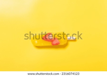 top view mango fruit flavor with strawberry slices popsicle melting timelapse on yellow background