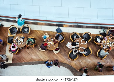 Top view of many Asian people sitting in food court cafe eating lunch near ice rink. City cafe. People having lunch at city cafe. People eating business lunch during work day. Aerial cafe lunch. - Powered by Shutterstock