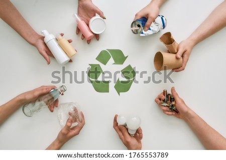 Top view of many hands holding different waste, garbage types with recycling sign made of paper in the center over white background. Sorting, recycling waste concept. Horizontal shot. Top view Foto stock © 