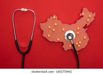 Top view of map of china with push pins and stethoscope on red background