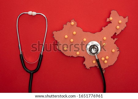 Top view of map of china with push pins and stethoscope on red background
