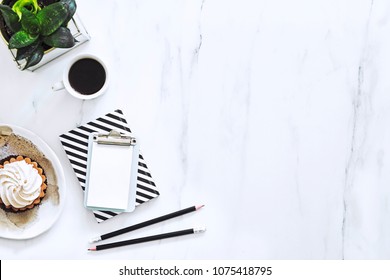 The Top View Of Marble Desk With Cup Of Coffee, Cake And Notebooks. Design Interior Of Modern Desk With Copy Space For Social Media Slogan.