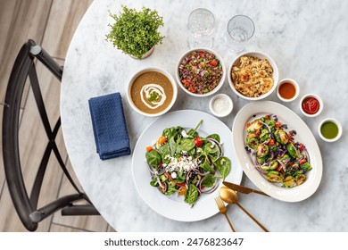 A top view of a marble dinner table with gourmet salad dishes and sauces