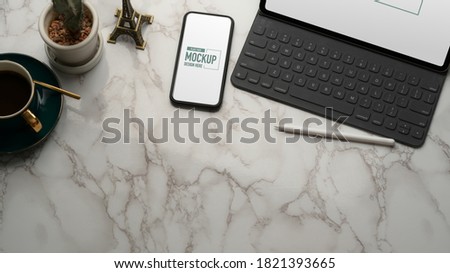 Top view of marble table with mock up tablet, smartphone, office supplies and copy space 