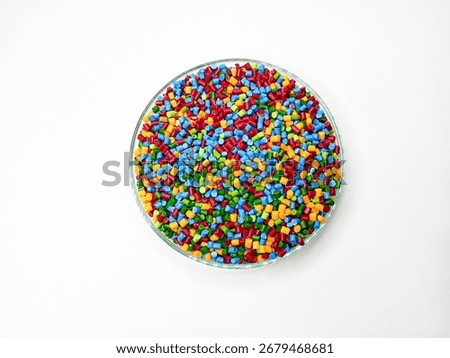Top view, masterbatch granules, polymer carrying pigment poured into a glass cup forming a circle with a white background, as a product catalog design for a plastic industry company profile