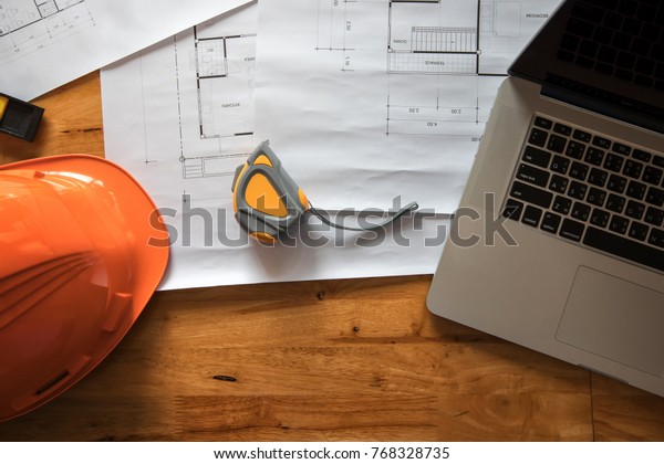 Top view of measurement tool with\
helmet and laptop on blueprint, architectural\
concept