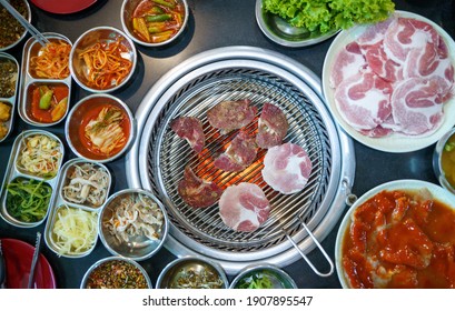 top view of meat steaks assorted on the hot grill grate with fire flames - Korean barbecue