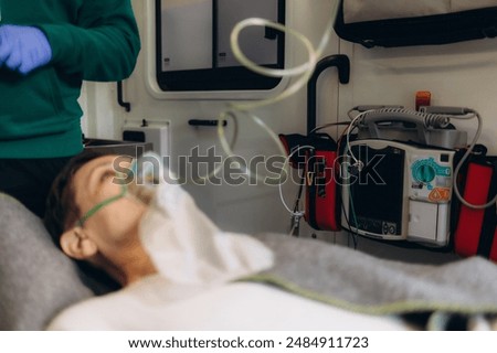 Top view of medic worker using valve mask bag on injured aged woman. Senior wounded female lying unconscious on hospital bed while doctor using oxygen bag