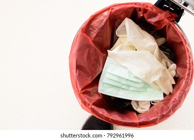 Top View Medical Gloves, Dispose Mask And Infectious Waste In Red Plastic Bag Infection Bin.