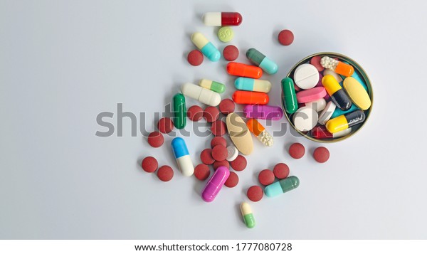 Top view of Medicines in bottle cover cap,\
colorful pills, tablets and capsules isolated in white background.\
Drug prescription use for medication in medical clinic, pharmacy\
pharmaceutical service.