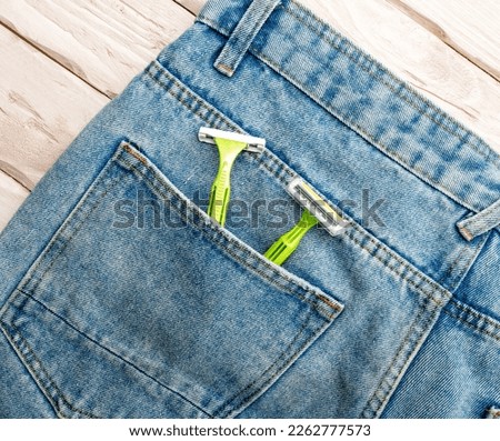 Top view Men's green razors with a blade for shaving in the pocket of denim pants. Men's razor in pants pocket.