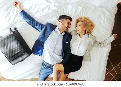 Top View Of Middle-aged Couple Dressed Formal Lying Down On The Bed And Hugging. They Gonna Have A Wonderful Weekend.