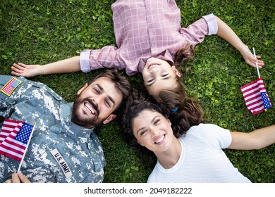 Top View Of Military Family Lying On The Grass Spending Time Together With Soldier Coming Home.