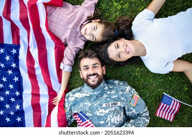 Top View Of Military Family Lying On The Grass Enjoying Time Together With Soldier Coming Home.