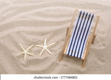 Top View Of Mini Beach Deck Chair And Two Starfish On Sand