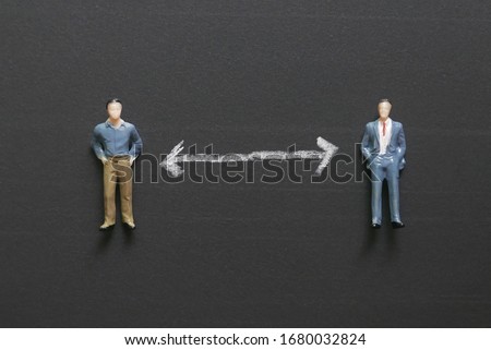 Top view of miniature people on a chalkboard with white arrow represent social distance of coronavirus or covid-19 issue. Social distancing concept.