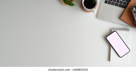 Top View Of Minimal Workspace With Blank Screen Smartphone, Laptop On White Color Desk 