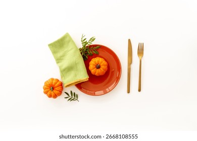 Top view of minimalistic table setting with empty plate and napkin with green leaves on brown background, flat lay.
