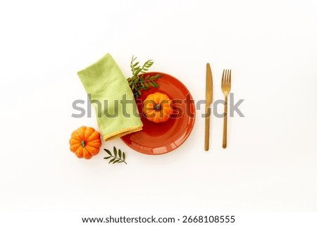 Top view of minimalistic table setting with empty plate and napkin with green leaves on brown background, flat lay.