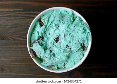 Top View of Mint Chocolate Chip Ice Cream in a Large Cup on Dark Brown Wooden Table